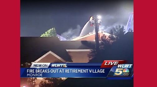 News coverage screengrab with the title 'Fire breaks out at retirement village Monroe,' and firetrucks extinguishing the fire in the background.